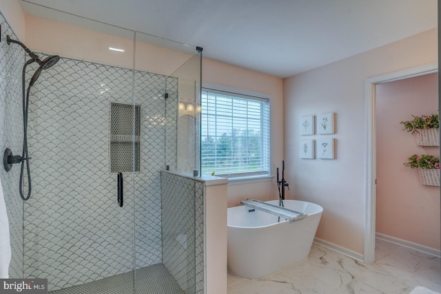 bathroom with a shower stall, a freestanding tub, and marble finish floor