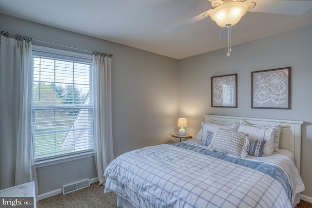 carpeted bedroom featuring ceiling fan, baseboards, multiple windows, and visible vents