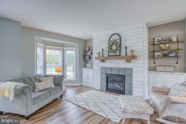 living room with baseboards, wood finished floors, and a tiled fireplace