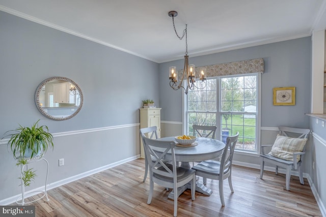 dining area featuring light wood-style floors, crown molding, a notable chandelier, and baseboards
