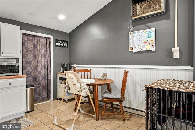 7443 Tamara Ln, Tobyhanna, PA 18466 - dining space featuring light tile patterned floors, wainscoting, and vaulted ceiling
