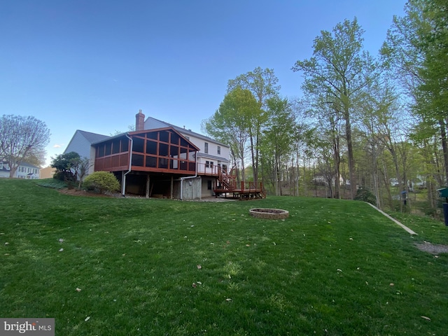 view of yard featuring a fire pit, a sunroom, and a deck