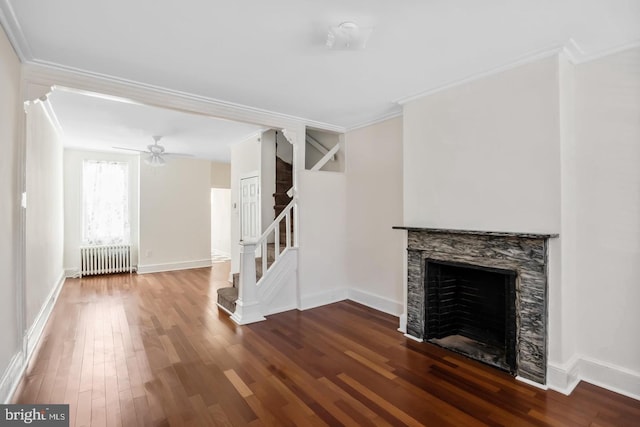 unfurnished living room featuring a fireplace, ornamental molding, radiator, and wood finished floors