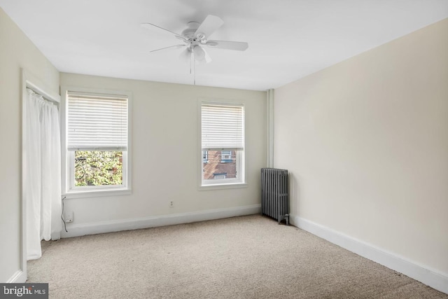 carpeted empty room featuring radiator heating unit, ceiling fan, and baseboards
