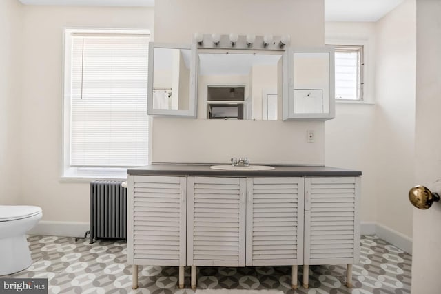 bathroom featuring toilet, baseboards, radiator, and vanity