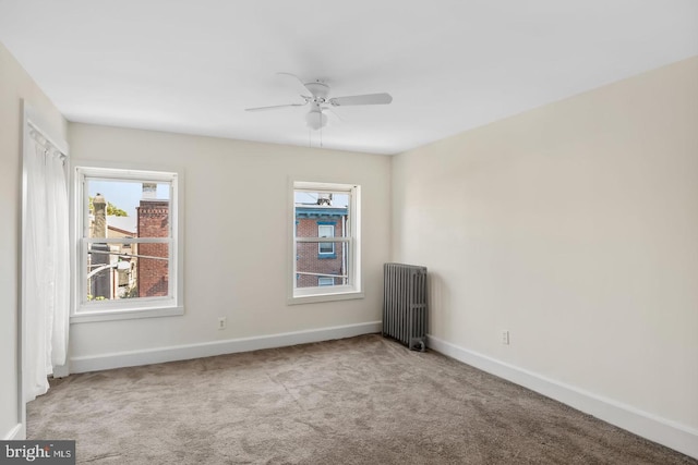 unfurnished room featuring a wealth of natural light, carpet, baseboards, and radiator