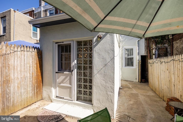 entrance to property with fence and stucco siding