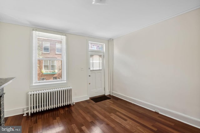 interior space featuring baseboards, ornamental molding, a fireplace, radiator, and wood finished floors