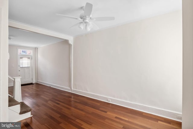 spare room featuring wood finished floors, baseboards, a ceiling fan, and stairway