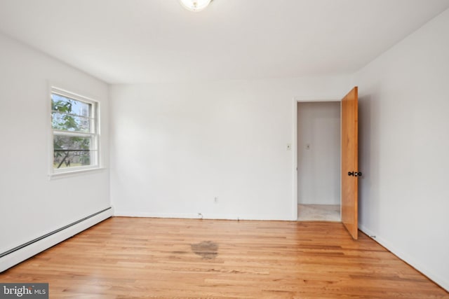 spare room with wood finished floors and a baseboard radiator