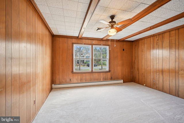 spare room featuring carpet floors, wood walls, baseboard heating, and ceiling fan