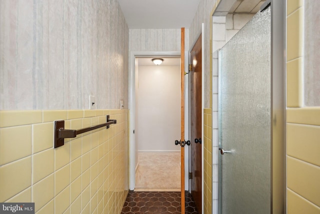 bathroom featuring wallpapered walls, tile walls, tile patterned flooring, and a stall shower