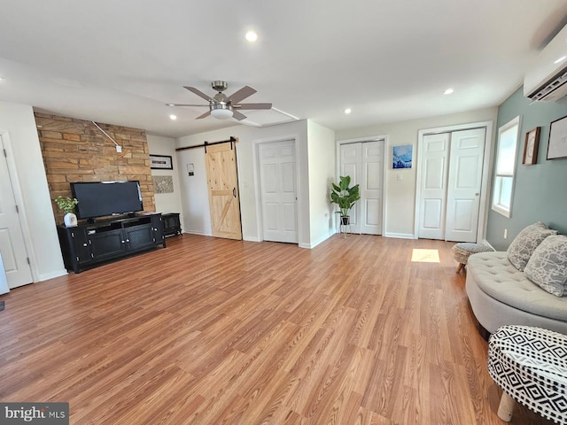 living room with a wall mounted AC, recessed lighting, ceiling fan, and a barn door