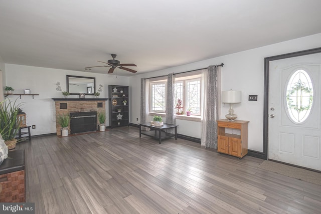 entryway with a healthy amount of sunlight, wood finished floors, a ceiling fan, and a brick fireplace