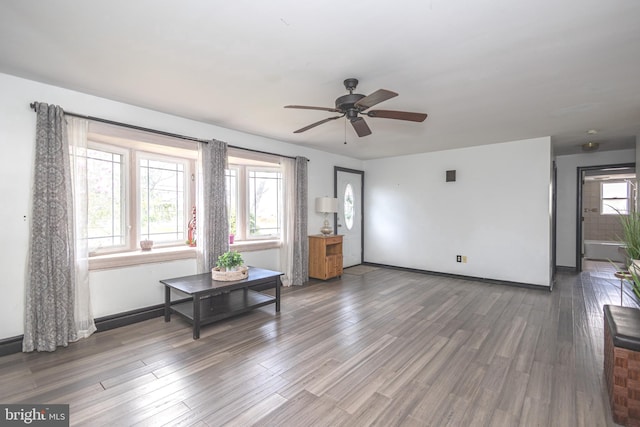 living area featuring wood finished floors, ceiling fan, and baseboards