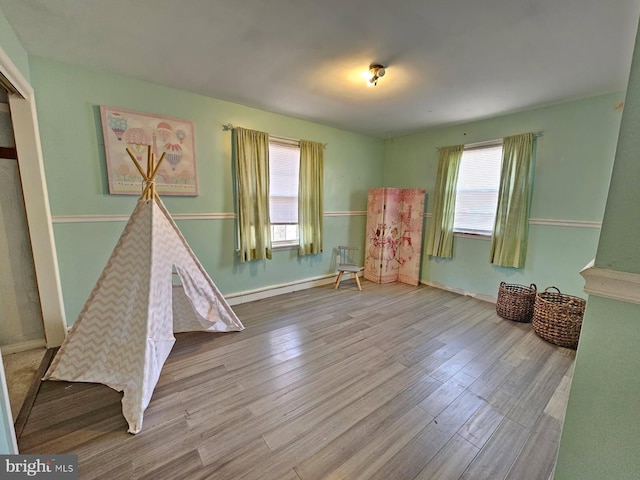recreation room featuring a baseboard radiator, wood finished floors, and baseboards