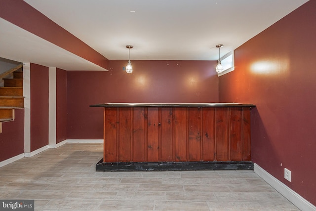 bar with baseboards, stairs, decorative light fixtures, light wood-style floors, and a dry bar