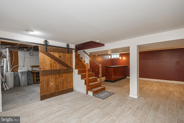 finished below grade area featuring baseboards, stairway, bar area, and wood finished floors