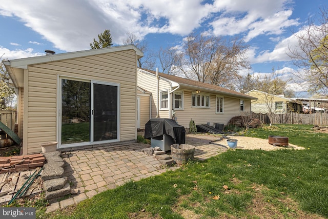 rear view of house featuring an outdoor fire pit, a patio, fence, and a lawn
