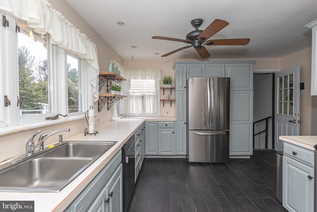 kitchen featuring freestanding refrigerator, open shelves, ceiling fan, dishwasher, and a sink