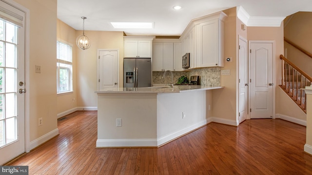 2080 Capstone Cir, Herndon, VA 20170 - kitchen with appliances with stainless steel finishes, light wood finished floors, a peninsula, tasteful backsplash, and white cabinetry