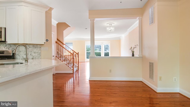 2080 Capstone Cir, Herndon, VA 20170 - kitchen with a sink, decorative columns, light wood-style flooring, white cabinets, and crown molding