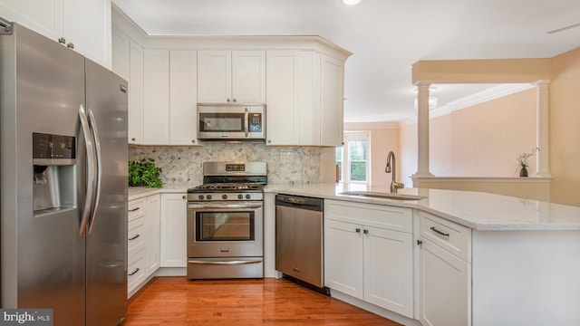 2080 Capstone Cir, Herndon, VA 20170 - kitchen featuring appliances with stainless steel finishes, a sink, a peninsula, ornate columns, and backsplash