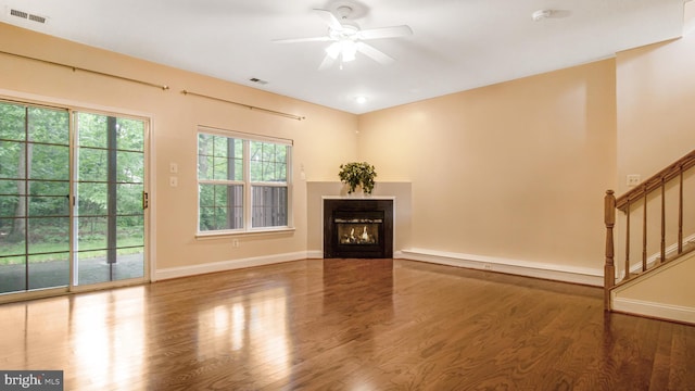 2080 Capstone Cir, Herndon, VA 20170 - unfurnished living room featuring a ceiling fan, wood finished floors, a glass covered fireplace, baseboards, and stairway
