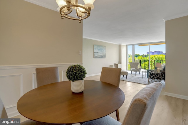 dining room featuring light wood-style floors, expansive windows, baseboards, an inviting chandelier, and ornamental molding
