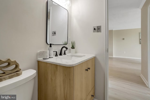 bathroom with vanity, baseboards, toilet, and wood finished floors