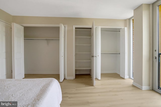 bedroom with light wood-style floors, multiple closets, and baseboards