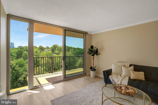 living area featuring ornamental molding, wood finished floors, and a healthy amount of sunlight
