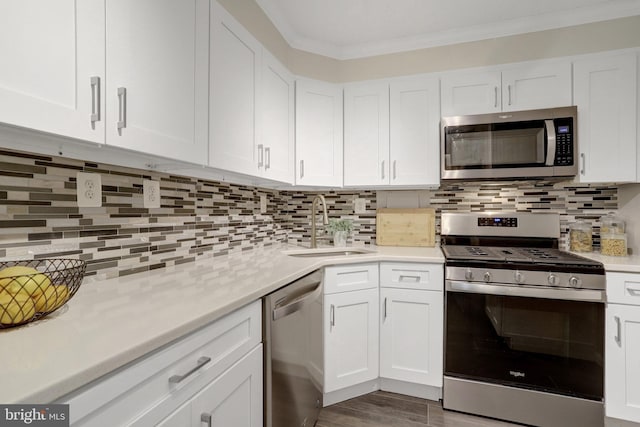 kitchen featuring crown molding, light countertops, white cabinets, a sink, and stainless steel appliances