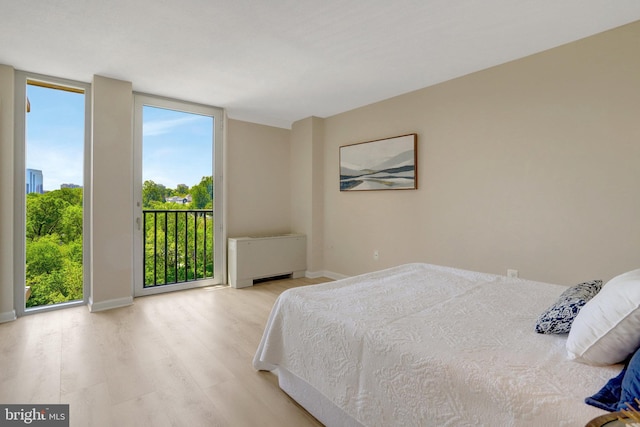 bedroom with baseboards, radiator, light wood finished floors, and access to exterior