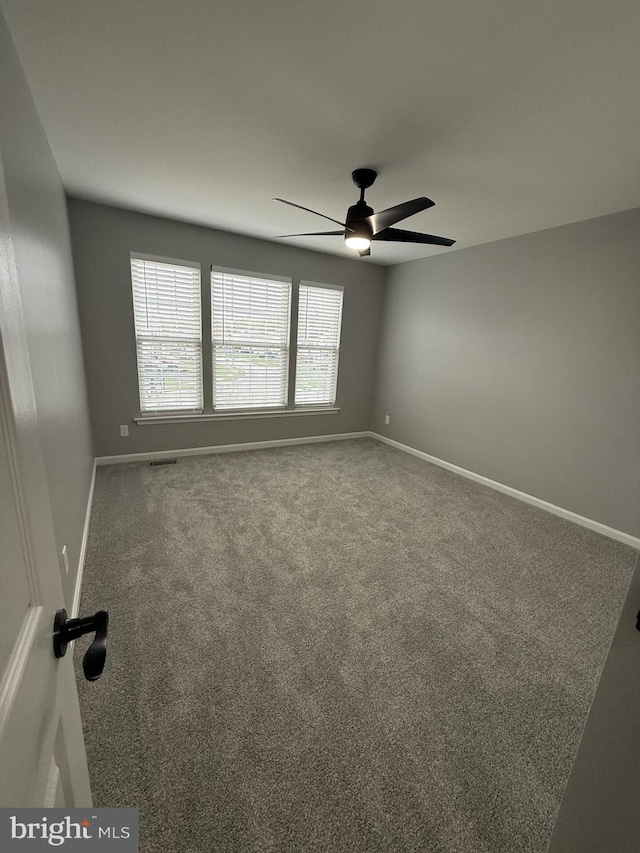 spare room with visible vents, carpet floors, ceiling fan, and baseboards