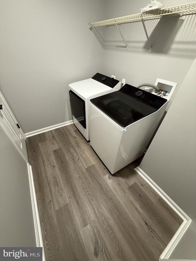 laundry room with laundry area, wood finished floors, baseboards, and washing machine and dryer