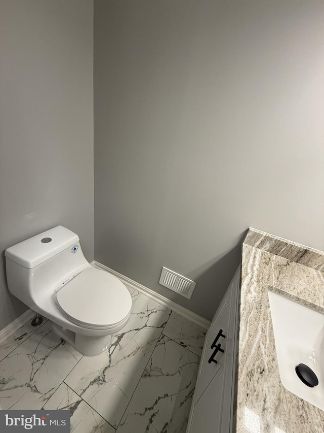 bathroom with visible vents, baseboards, a sink, toilet, and marble finish floor