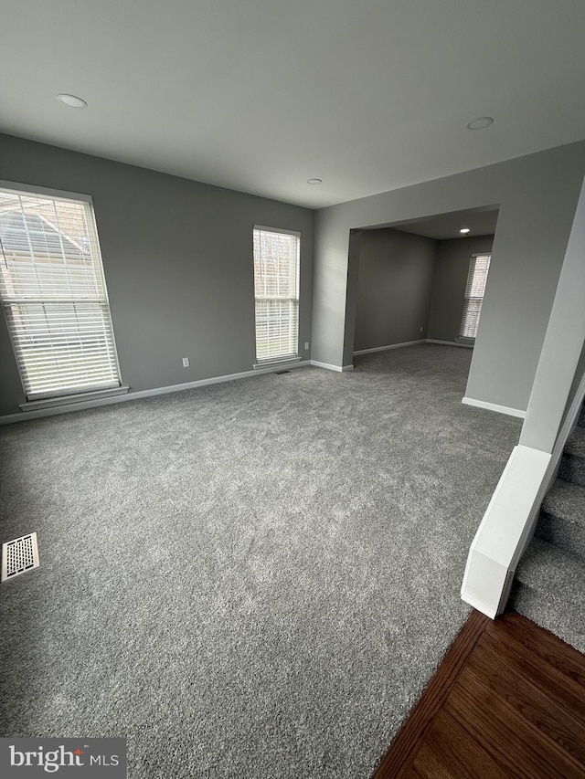spare room featuring a healthy amount of sunlight, baseboards, carpet, and visible vents