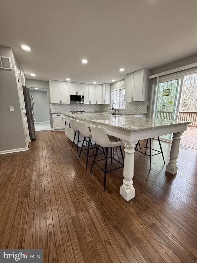 kitchen featuring a sink, a kitchen breakfast bar, decorative backsplash, and appliances with stainless steel finishes