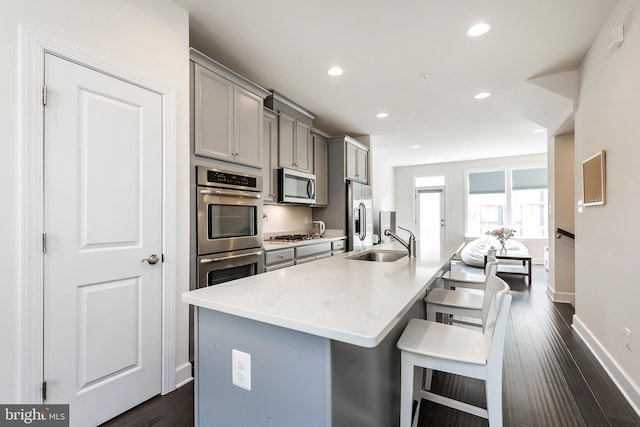 6645 Rhode Island Ave, Riverdale, MD 20737 - kitchen featuring a kitchen breakfast bar, a sink, gray cabinetry, a kitchen island with sink, and appliances with stainless steel finishes