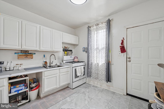 kitchen with light countertops, white cabinetry, a sink, and gas range gas stove