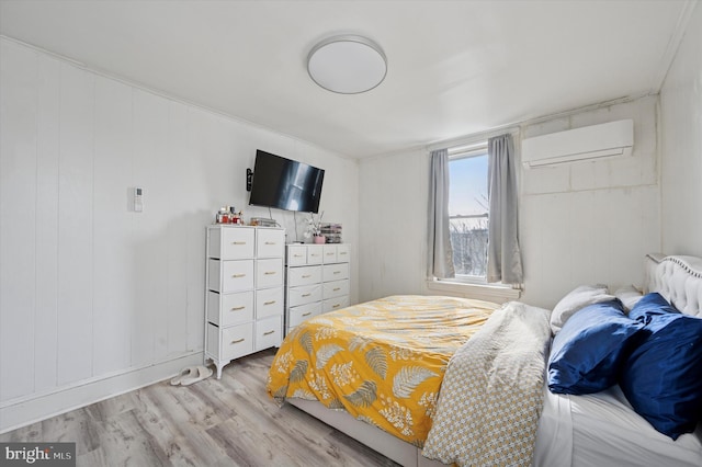 bedroom with light wood-style floors and a wall mounted air conditioner