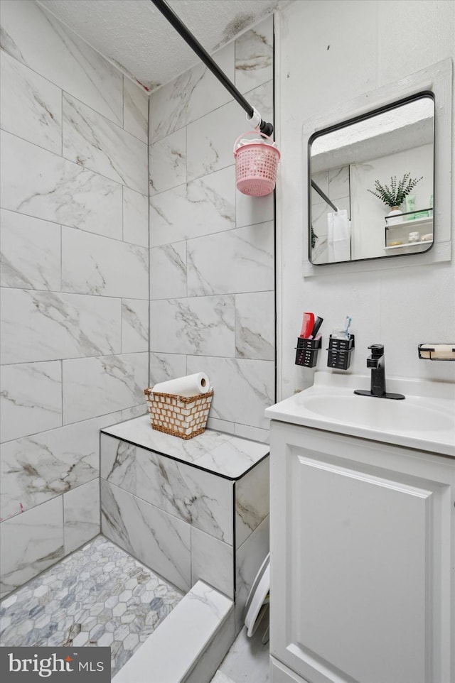 bathroom with vanity and tiled shower