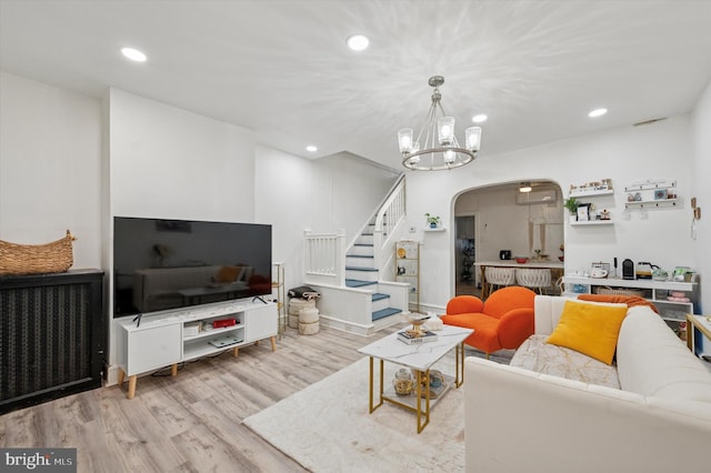 living area with arched walkways, radiator, stairs, recessed lighting, and wood finished floors