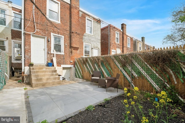 back of property with brick siding, fence, a patio area, and entry steps