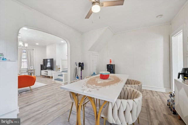 dining room with a ceiling fan, arched walkways, and wood finished floors