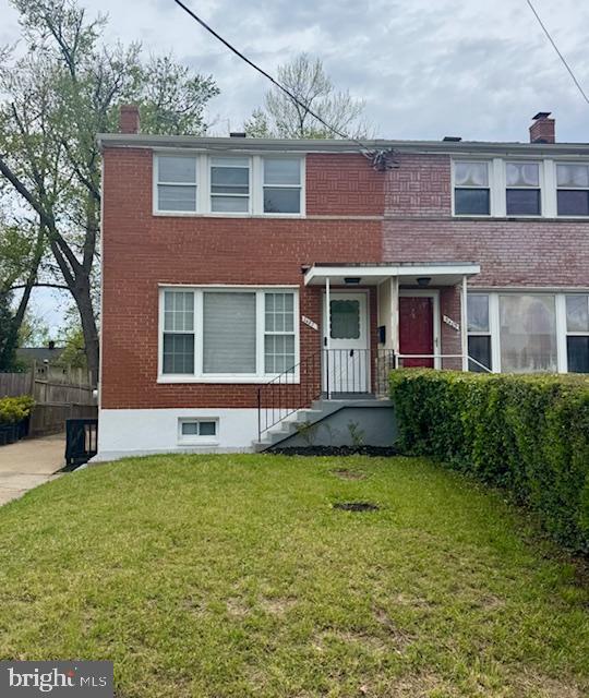 view of front of property with a chimney, a front lawn, and brick siding