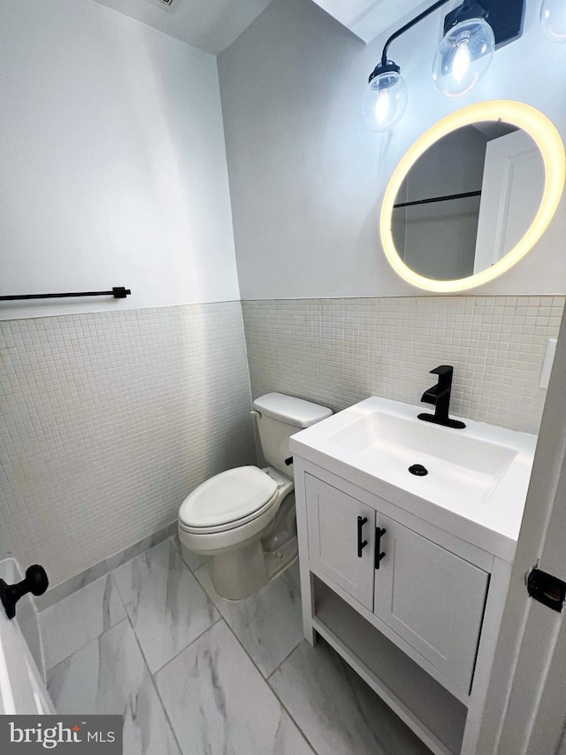 1447 Holbrook St NE, Washington, DC 20002 - bathroom with vanity, toilet, marble look tile flooring, tile walls, and wainscoting