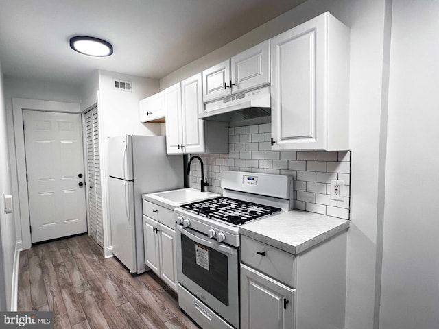 1447 Holbrook St NE, Washington, DC 20002 - kitchen featuring white appliances, under cabinet range hood, wood finished floors, and white cabinetry