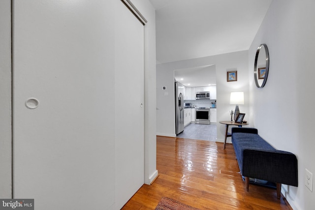 hall featuring baseboards, recessed lighting, and light wood-style flooring